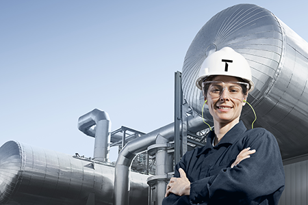 Smiling Topsoe engineer with hard hat standing in front of large industrial equipment
