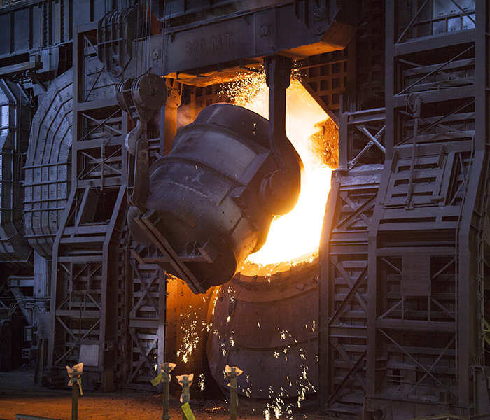 High-temperature material pouring from a tilting furnace into a heated chamber