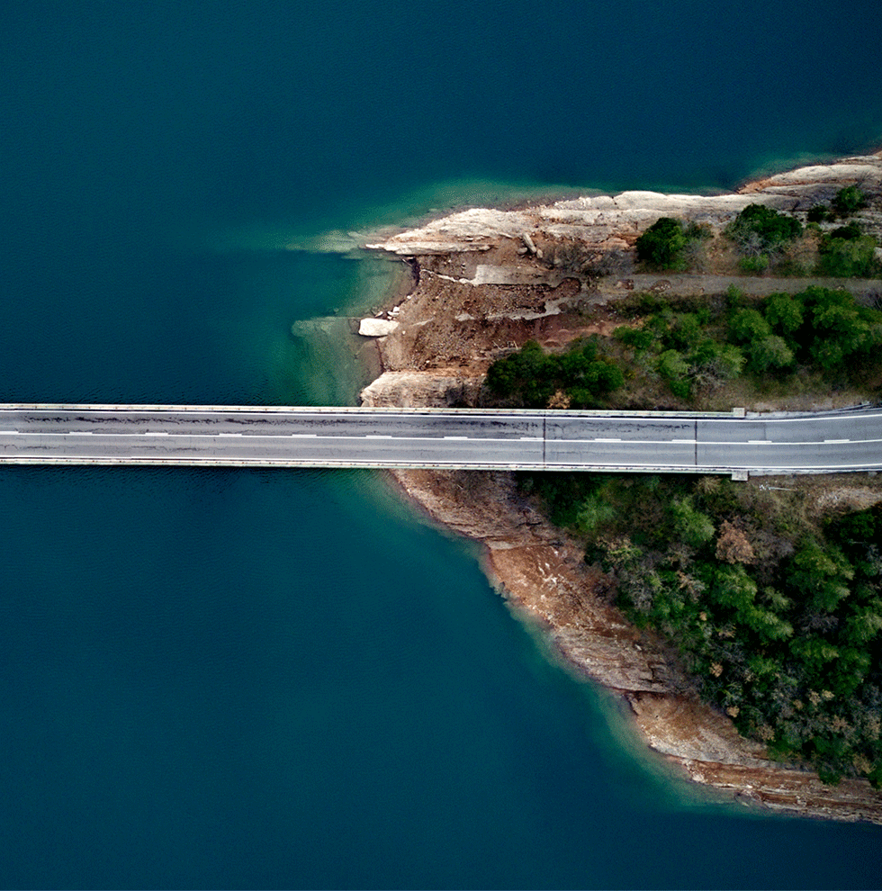 Bridge seen from above over blue water and green landscape