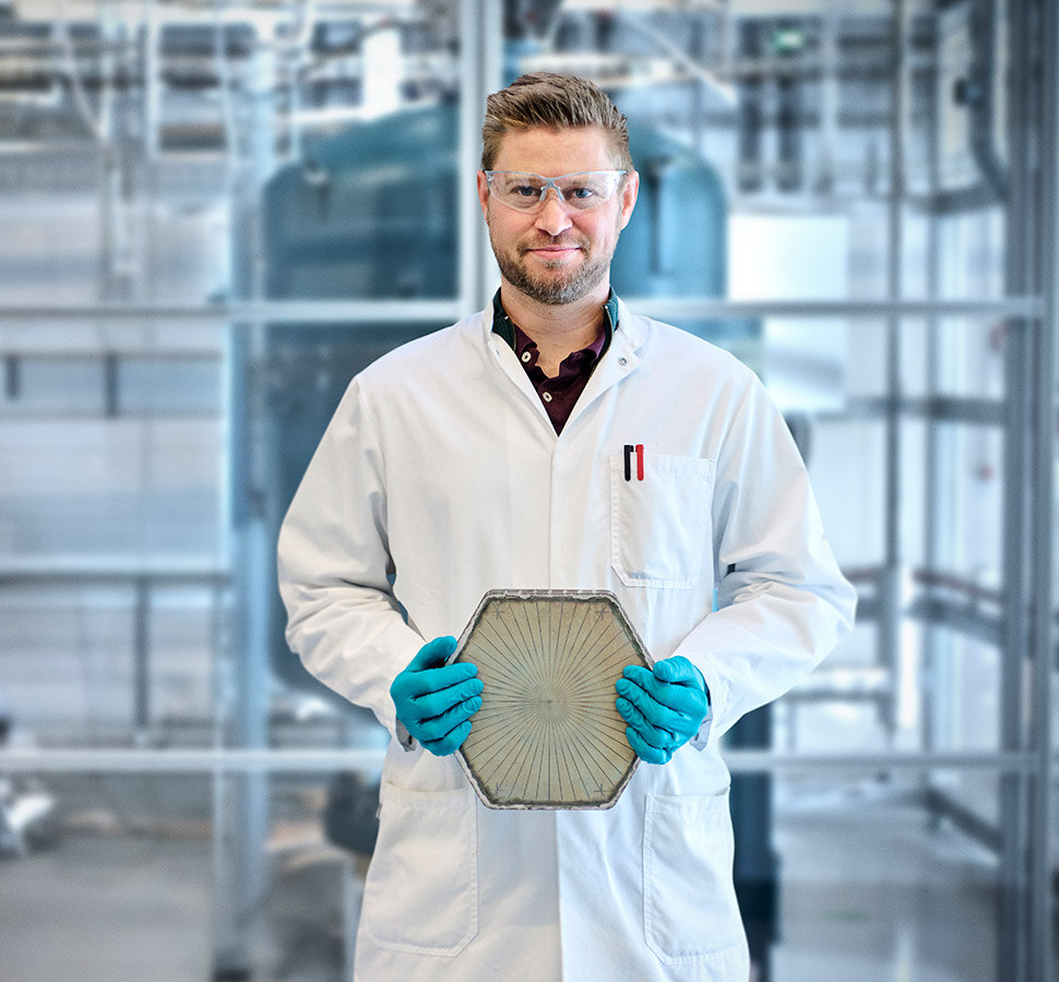 Scientist holding a hexagonal SOEC component in an industrial laboratory